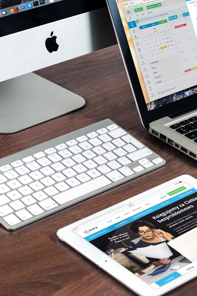 A sleek office desk setup featuring Apple devices: iMac, MacBook, and iPad.